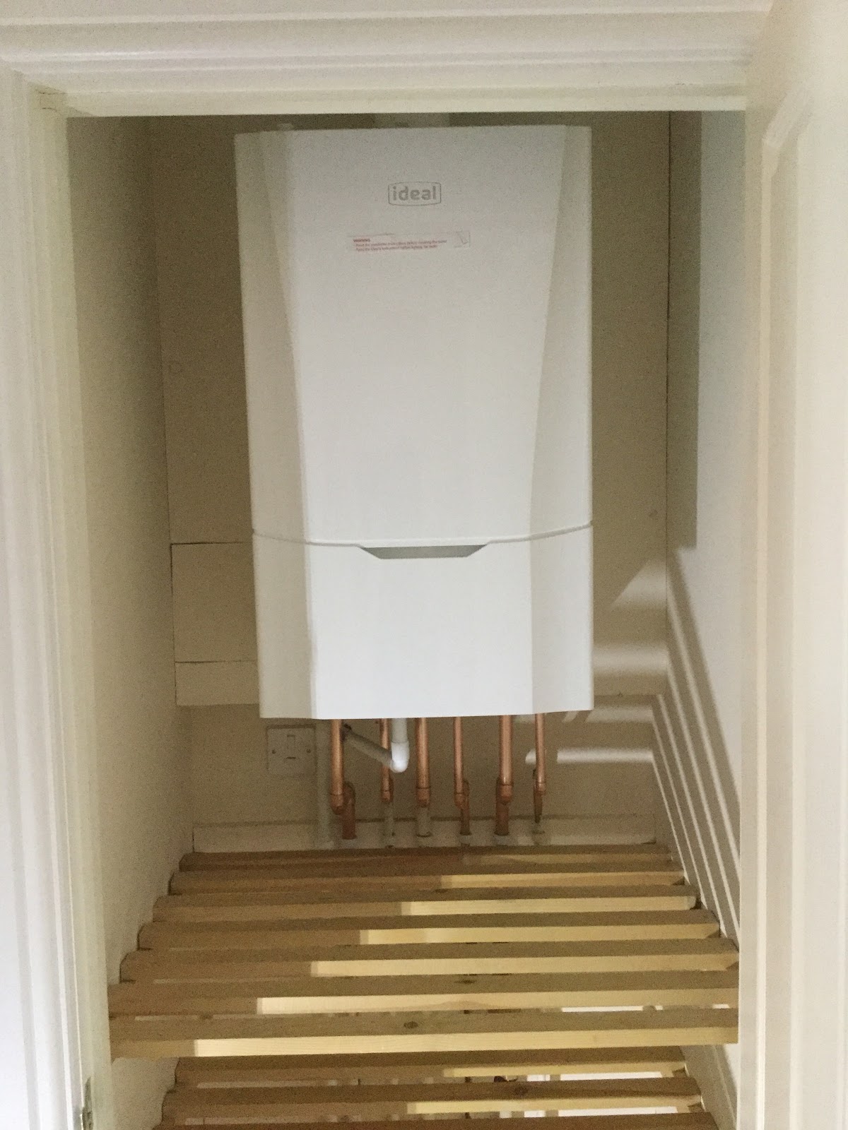 A fitted Ideal boiler with copper pipework in a cupboard
